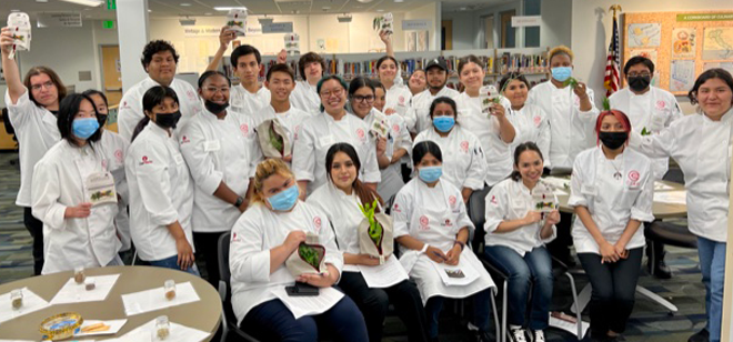 C-CAP participants in white C-CAP jackets posing for the camera with produce and produce bags.