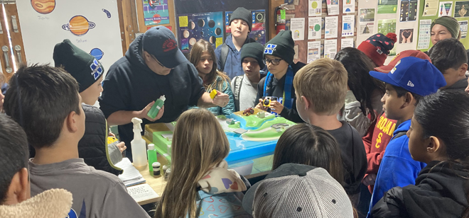 Students gather around a watershed model, exploring environmental education concepts at the Skyland Ranch