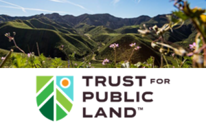 A view of green mountains in the mid and background. In the foreground, flowers with pink blooms, all beneath a bright blue sky. Below the image, the log of Trust for Public Land over white.